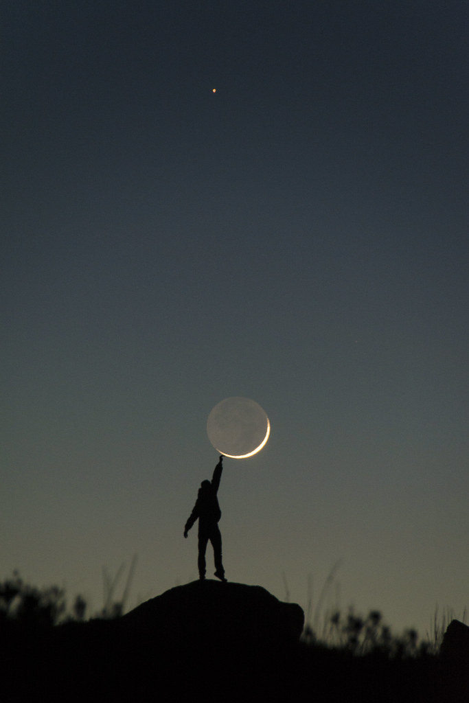 A crescent moon with cracks and a person reaching out to touch it.