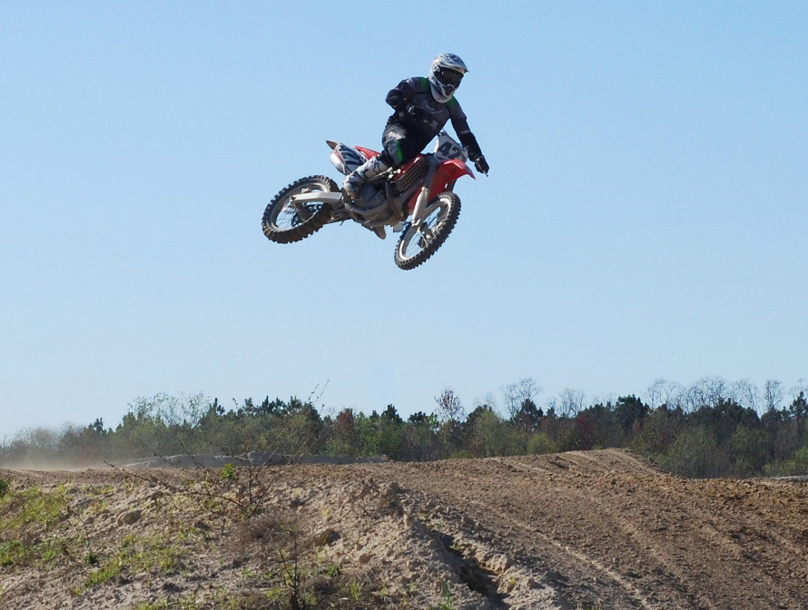 A dirt bike jumping over a large obstacle.