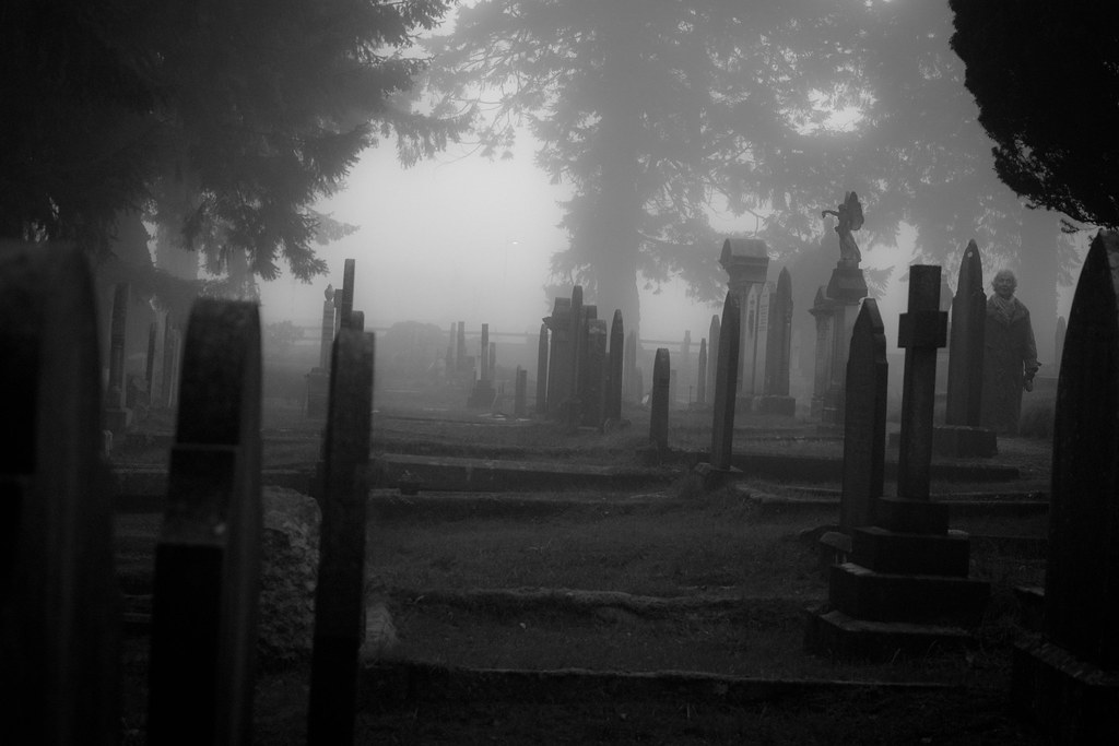 A ghostly figure standing in a misty graveyard.