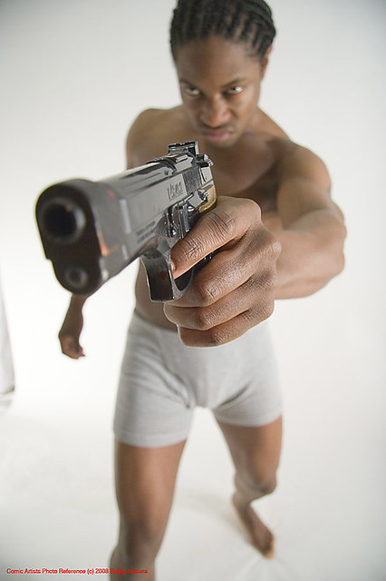 A gun pointing towards a silhouette of a person.