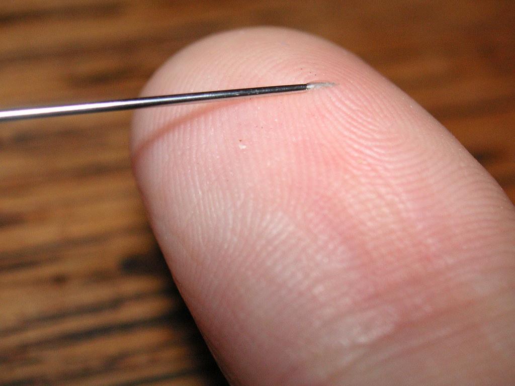 A needle piercing through a hand or finger.