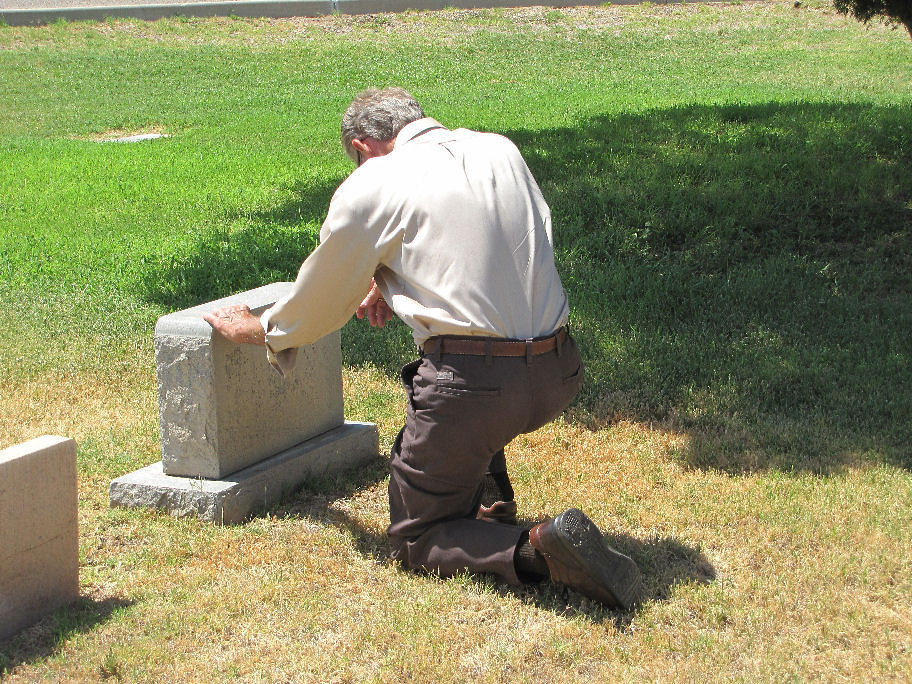 A person crying next to a gravestone.