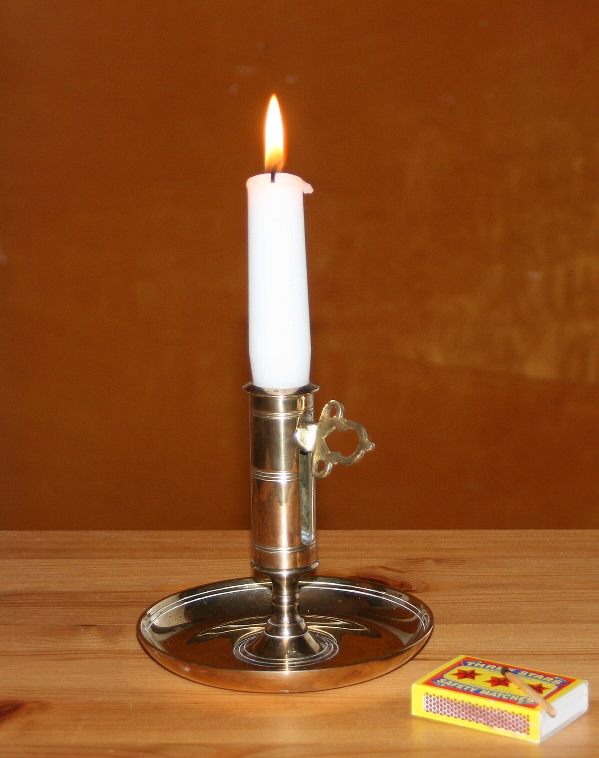 A person holding a small candle in a dark room.