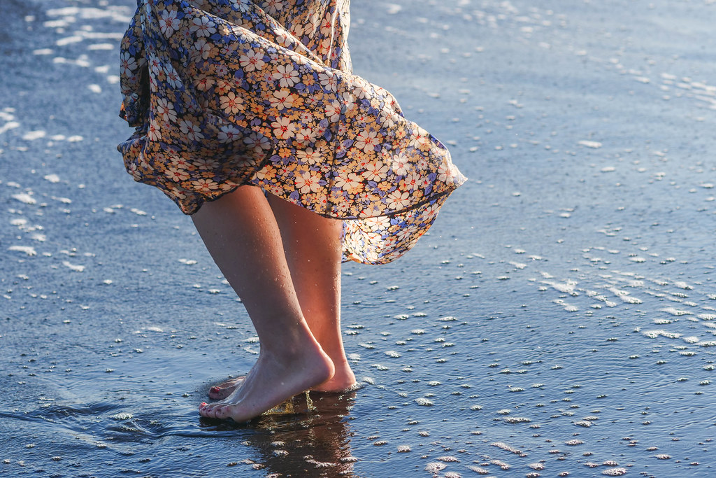 A person walking barefoot on a beach.