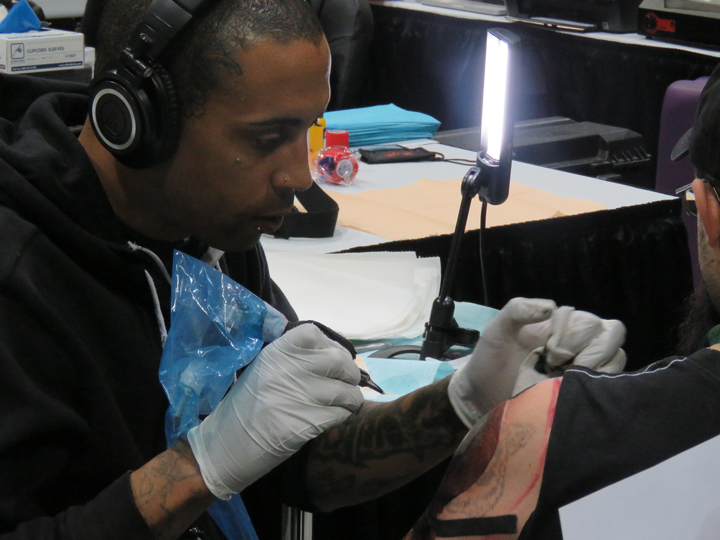 A tattoo artist working on a chest tattoo.