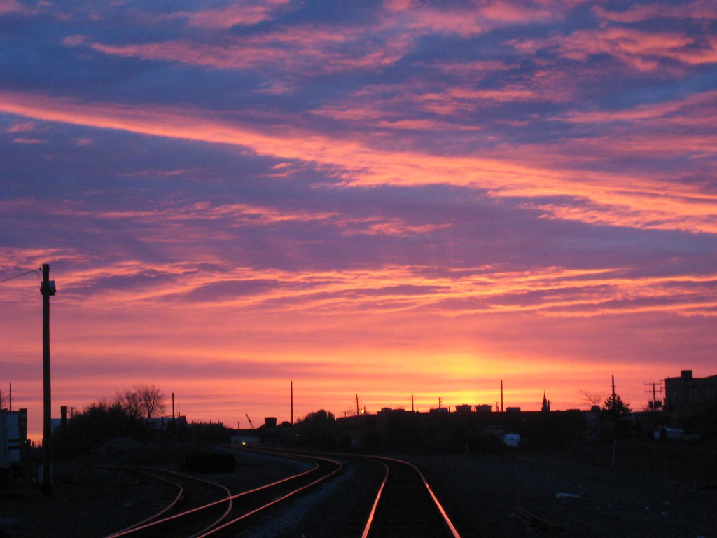 A train track leading towards a beautiful sunrise.