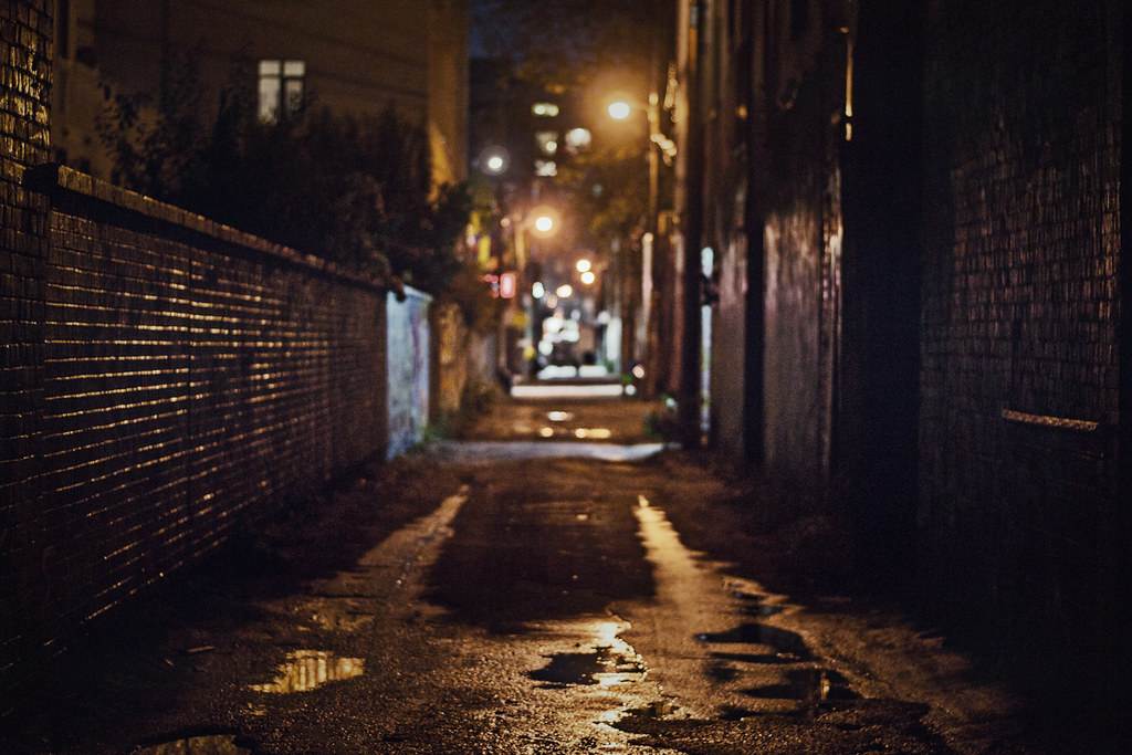 Dark alleyway with graffiti-covered walls.