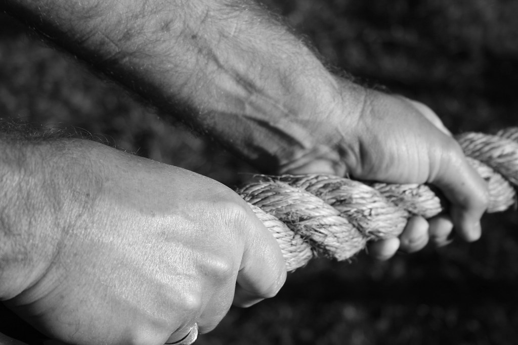 Image of a person struggling to hold onto a slipping rope.